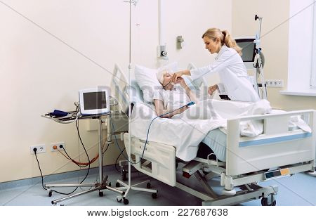 Let Me Help You. Positive Minded Physician Helping Elderly Woman With An Oxygen Mask While She Lying