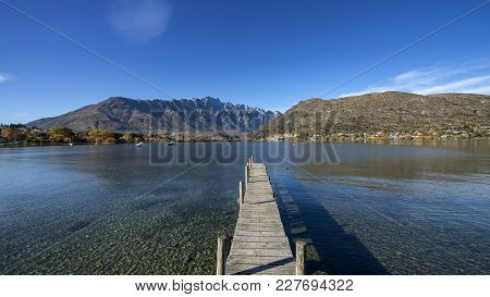 Low Wooden Jetty In Frankton, Near Queenstown, Otago, South Island, New Zealand. Clear Lake Water An