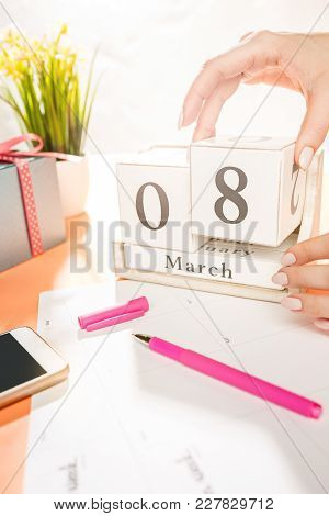 The Side View Of Orange Desk With Cup Of Phone, Gift, Flowers And Notebook
