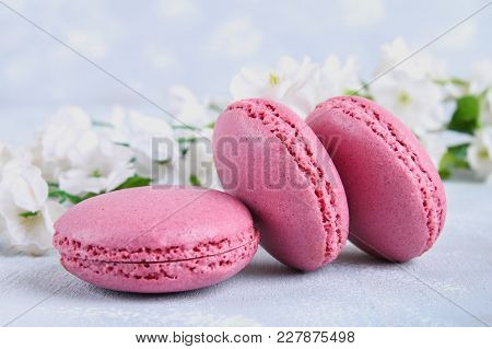 Pink And Purple Macaroons On A Gray Table Surrounded By Pink And White Flowers