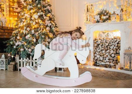 Beautiful Baby Girl Near A Christmas Tree With Gifts
