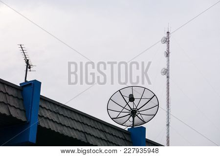 Sattlelite And Tv Antenna And Cellular Communication Antenna On The Roof With Cloud Sky.