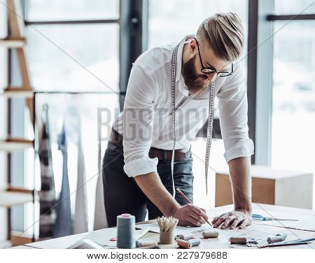 Cropped Image Of Handsome Male Fashion Designer Is Working In His Workshop. Stylish Bearded Man In P