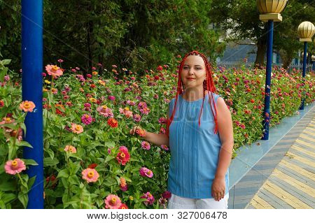 Young Woman With Red Hair Among Red Orange Colors.