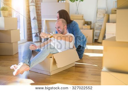 Funny and crazy couple having fun riding a cardboad box as a car, smiling happy and lauging at new home