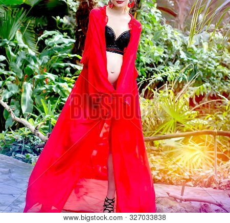 Pregnant Blonde Girl In A Red Tunic And With Earrings In The Tropics Walks