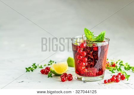 Cold Red Cocktail With Currant, Lime, Mint, Thyme And Ice In Glass On Light Gray Concrete Surface Ta