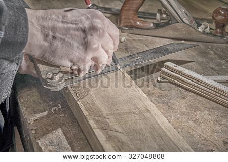 Carpenter Marking Measurements On Piece Of Wooden Board