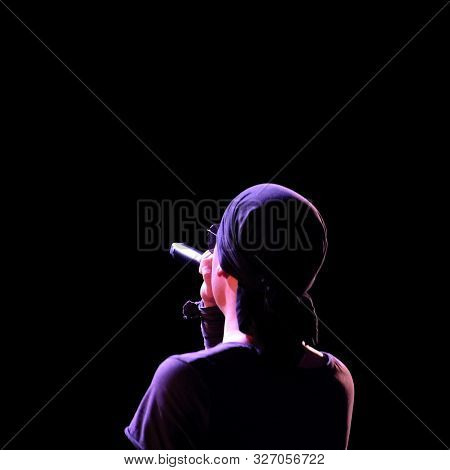 Silhouette Of A Rock Singer In Dark Clothes And A Bandana On A Black Background. Image Of An Abstrac