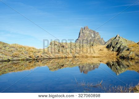 Midi Dossau Peak reflected in a lake. Ossau Valley, Pyrenees National Park, Pyrenees, France.