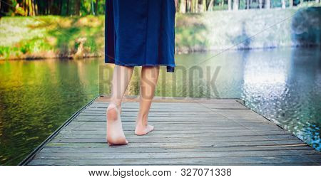 Young Girl Making A Step Bootlessly On The Wooden Pier And Moving Forward To The Water. Select Right