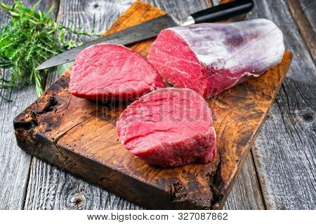 Dry aged beef fillet steak natural as closeup offered on an old rustic wooden cutting board