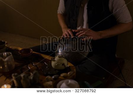 Man Playing Tank Drum Or Hang At Home. Warm Romantic Illumination, Low Key. Relaxation, Meditative A