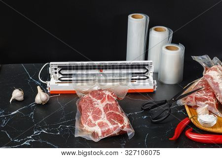 Vacuum Sealer Machine And Meat Packed On A Dark Background.