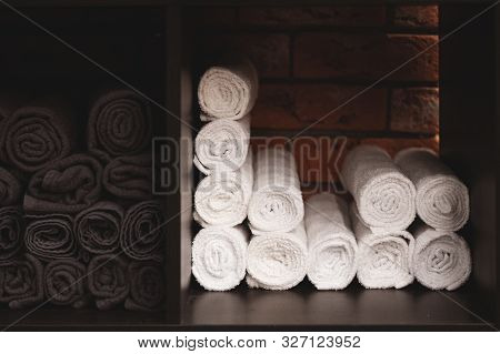White Towels Folded Into A Roll. Brickwork In The Background. Presentation Of Textiles. Rational Use