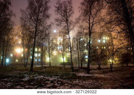 Multicolored Windows Of Apartment Buildings In The City During A Thick Fog At Night