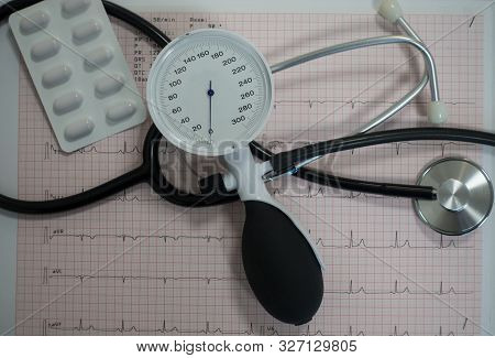 Sphygmomanometer With Aneroid Gauge, Stethoscope And Pills With Electrocardiogram Paper. Sphygmomano