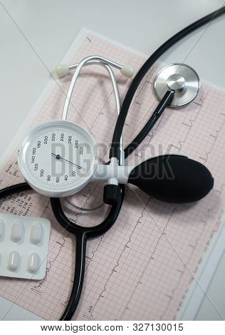 Sphygmomanometer With Aneroid Gauge, Stethoscope And Pills With Electrocardiogram Paper. Sphygmomano