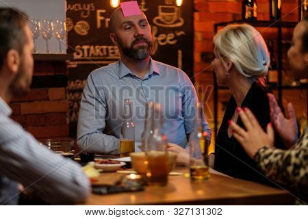Group of friends playing sticky head game behind bar counter in a cafe
