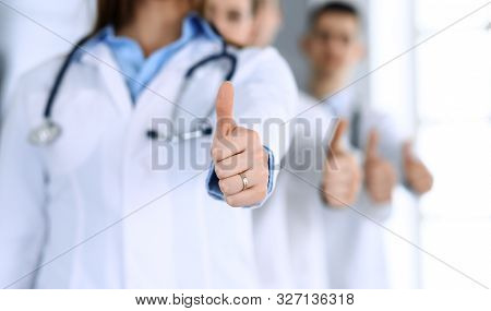 Group Of Modern Doctors Standing As A Team With Thumbs Up In Hospital Office. Physicians Ready To Ex