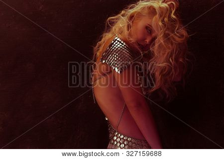 beautiful woman with silver scales on the man as a dragon armor, with the hair in the wind in sensual poses on rustic gray background