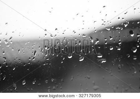 Wet Window With Rain Drops. Roof And Sky In Brurred Background. Rainy Weather.