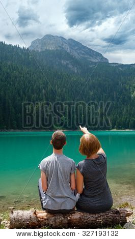 People, Mother With Son, Rest On Tree Log On Black Lake, Crno Jezero, Shore, Summer Landscape. Zablj