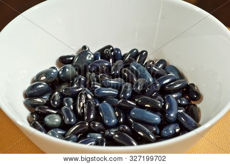 Many Beans Are Sorted By Species. Fresh Young Beans In A White Plate. Texture Of Black And Dark Blue