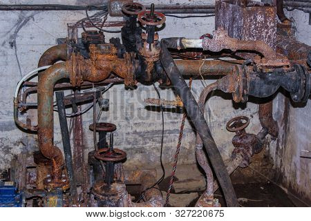 Rusty Pipes In The Basement Of The House. Old Plumbing, Taps, Valves