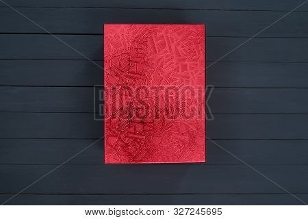 Red Closed Shiny Cardboard Box On A Black Wooden Background. Top View. Present