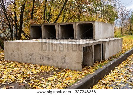 A Stack Of Reinforced Concrete Trays For A Heating Main On An Autumn Street. Preparation For Constru