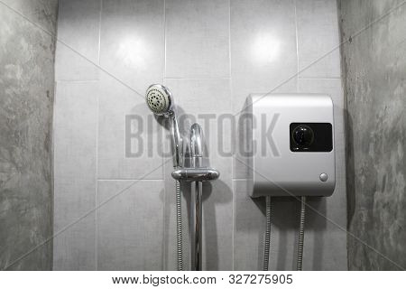 Instant Tankless Electric Water Heater Installed On Grey Tile Wall With Input And Output Pipe Outlet