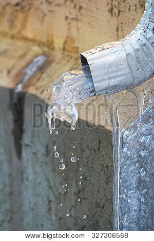 Ice Melting Though An Eavestrough In Spring