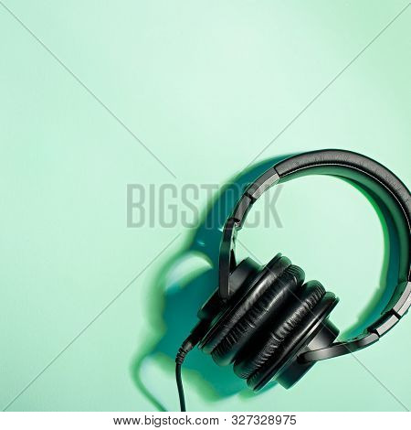 Black Over Ear Headphones Closeup On Blue Background, Top View. Minimal Music Background, Copy Space