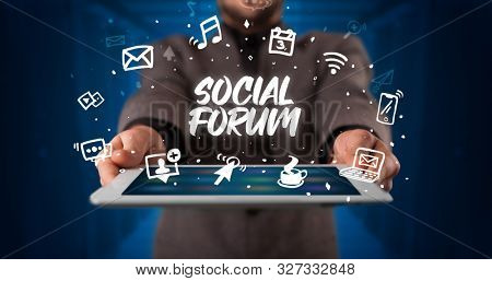 Young business person working on tablet and shows the inscription: SOCIAL FORUM