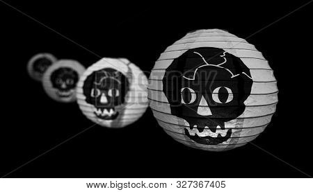Scary White Lanterns With A Skull On It.  4 Lanterns Hanging In A Line, Black Background.