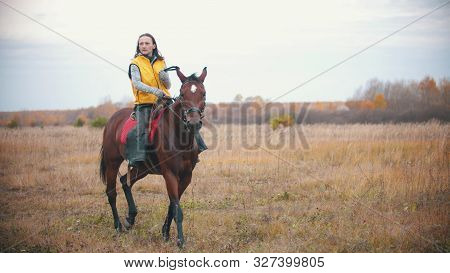 A Woman In Yellow Vest Is Riding A Bay Horse