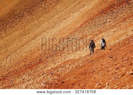 Two Tourists On Steep Volcanic Slope Of Tunupa Volcano In Bolivia