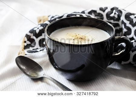 Cauliflower Soup (creme Du Barry) In Black Bowl On White Background With Black And White Cloth