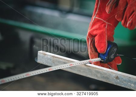 A Worker Checking Length By A Meter.