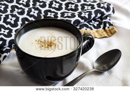 Cauliflower Soup (creme Du Barry) In Black Bowl On White Background With Black And White Cloth
