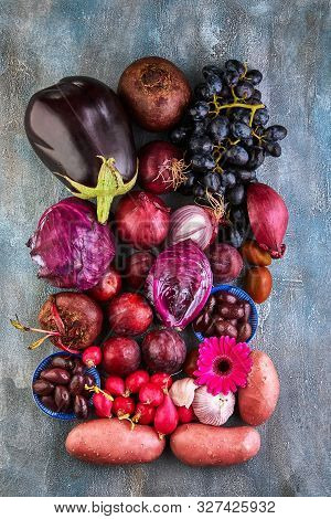 Vegetables And Fruits In Violet Pink Colors On A Blue Background. View From Above. The Concept Of He