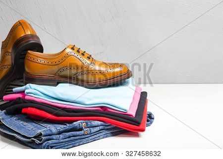 Pair Of Male Full Brogued Tan Oxford Shoes Placed On Top Of Heap Of Clothing. Horizontal Image Compo