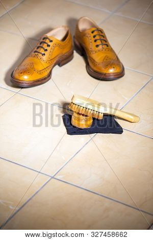 Pair Of Luxury Male Full Brogued Tan Oxford Shoes. Placed Together With Shoe Wax And Brush On Tiles 