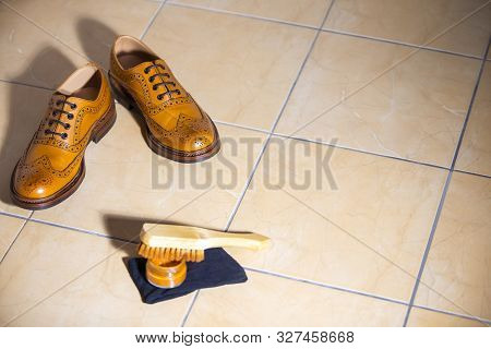 Pair Of Luxury Male Full Brogued Tan Oxford Shoes. Placed Together With Shoe Wax And Brush On Tiles 