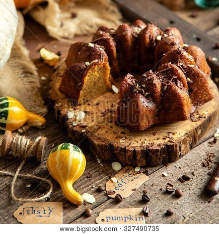 Tasty Homemade Baked Pumpkin Bundt Cake With Chocolate On Top Stands On Wooden Board On Rustic Table