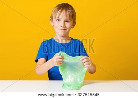 Funny Boy Playing With Green Slime Over Yellow Background. Happy Childhood.