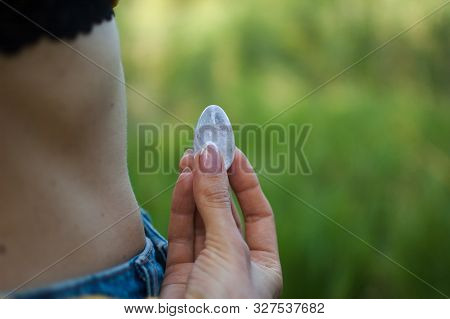 Side View Of Adult Woman Holding Transparent Violet Amethyst Yoni Egg For Vumfit, Imbuilding Or Medi