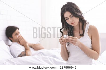 Love And Care. Attentive Girl Bringing Medicaments To Sick Boyfriend Lying In Bed, Reading Instructi