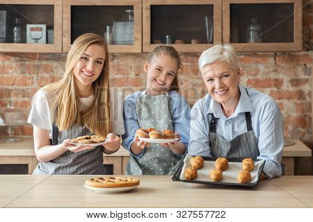 Happy Female Family Showing Freshly Baked Home Pastry, Granny, Mom And Daughter Cooking At Kitchen T